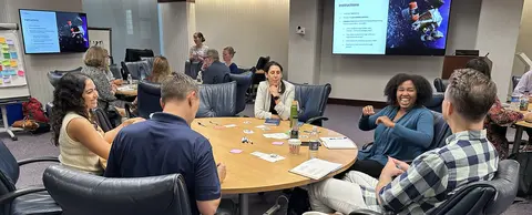 Participants from the 2025 Not-a-Bot summit sit and talk around a round table.