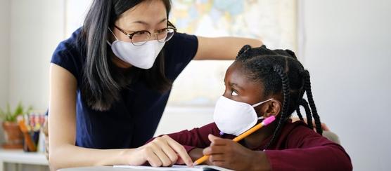 An educator and student wear masks while working together during COVID-19